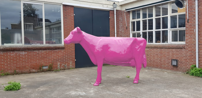 Een Vrolijke Beelden koe in het roze geschilderd