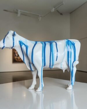 Wit koe beeldje met blauwe drip verf decoratie voor interieur